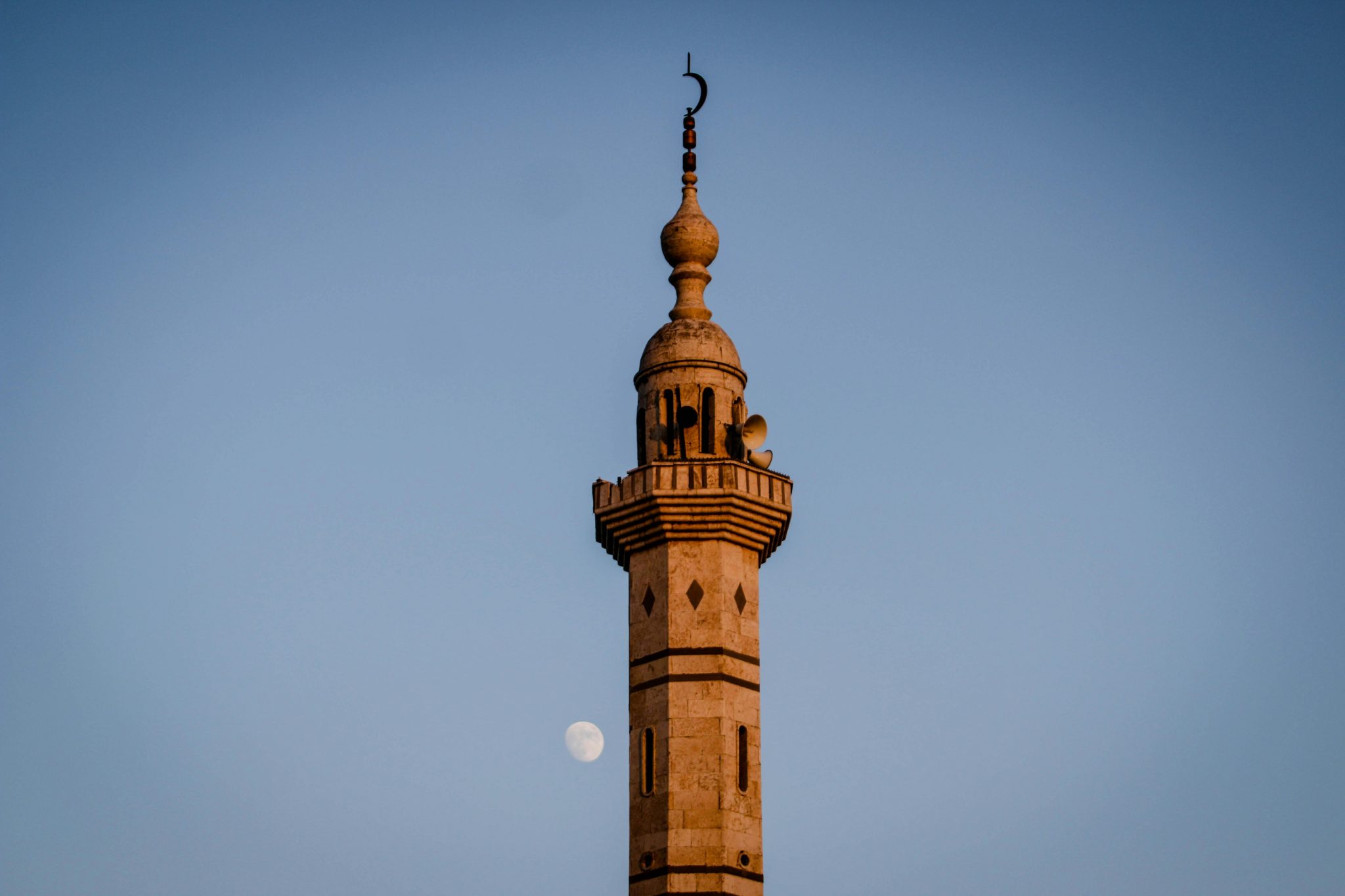 A stunning minaret in Idlib, Syria, framed against a clear sky with the moon visible.